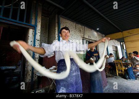 Uyghur Mann machen frische Laghman Nudeln auf dem Sonntagsmarkt in Kashgar in der Provinz Xinjiang in China Stockfoto