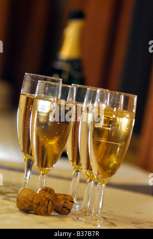 Vier Gläser gefüllt mit gekühltem Champagner auf eine Sommer-Hochzeit im Vereinigten Königreich. Es gibt zwei Korken im Vordergrund. Stockfoto