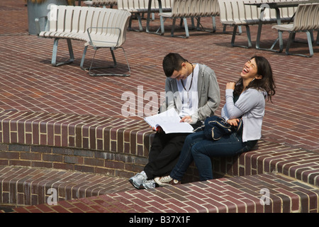 Eine junge Dame, die lachend sitzen auf Stufen mit ihrem Freund in der Barbican Estate City of London Stockfoto