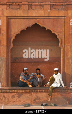 Drei Männer entspannen zwischen Gebetszeiten in Jama Masjid Moschee, Indiens größte Moschee. Es befindet sich in Old Delhi in der Nähe des Red Fort. Stockfoto