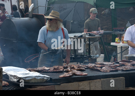 Mann kochen eine große Menge von Rippen bei einem Volksfest. Stockfoto