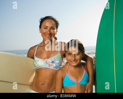 Hispanische Mutter und Tochter halten Surfbretter Stockfoto