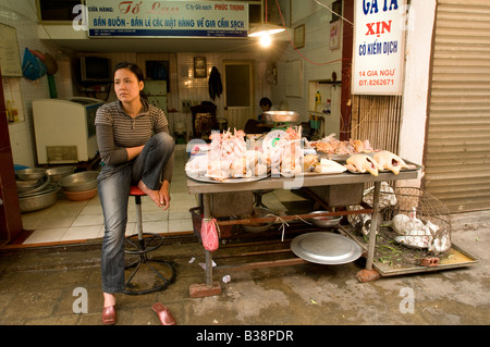 Eine vietnamesische Frau, die gelangweilt auf ihrem Hühnerstall im alten Viertel von Hanoi Vietnam Stockfoto