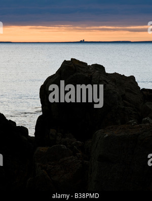 Felsen am Strand von Bamburgh zeigte auf eines der inneren Farne Inseln auf einen Sommer Dawn, Northumberland, England Stockfoto