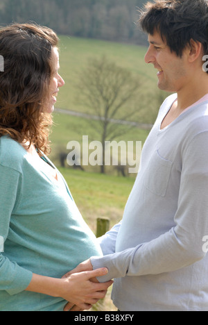 Schwangere Frau und Partner stehen von Angesicht zu Angesicht Hand in Hand Stockfoto