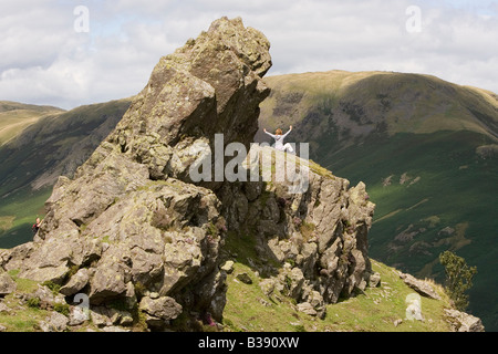 Eine Frau feiert auf dem Felsen, bekannt als die Haubitze an der Spitze Helm Felswand im Lake District Stockfoto