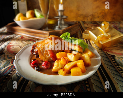 Gebratene Gresham-Entenschenkel serviert mit Winterfruchtsauce, Bratkartoffeln und Gemüse in festlicher Tischstimmung Stockfoto