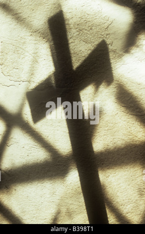 Schatten des Kreuzes werfen auf Creme lackiert rauhe Wand mit Projektion von einfachen Diamant verbleit Scheiben der Kirchenfenster Stockfoto