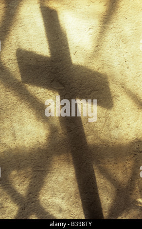 Schatten des Kreuzes werfen auf Creme lackiert rauhe Wand mit Projektion von einfachen Diamant verbleit Scheiben der Kirchenfenster Stockfoto