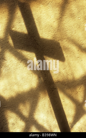 Schatten des Kreuzes werfen auf Creme lackiert rauhe Wand mit Projektion von einfachen Diamant verbleit Scheiben der Kirchenfenster Stockfoto