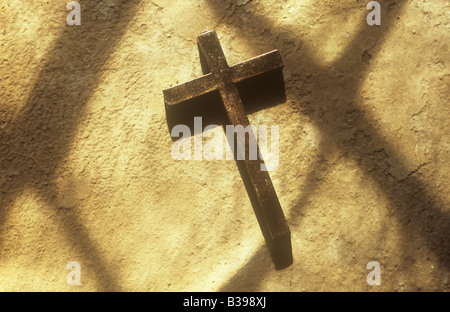 Einfache angelaufener Messing Kruzifix auf Creme liegend lackiert Stein Fensterbank oder Nische mit Schatten der Diamant verbleit Fenster Stockfoto
