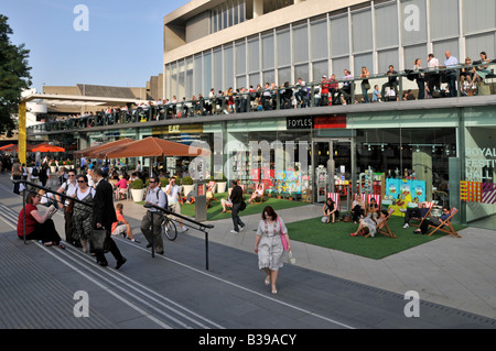 Sommer Mittagessen Zeit Menschen bei Foyles Buchhandlung in Liegestühlen & auf die Royal Festival Hall Terrasse am Flußufer South Bank am Ufer des Flusses Themse London UK Stockfoto