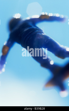 Klangschöne nahe des Modells der Skateboarder in blau Getriebe und Gelber Helm und Pads gegen blauen Himmel springen Stockfoto