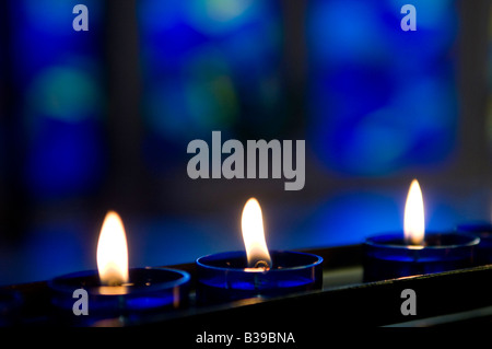 3 Kirche Kerzen vor einem blauen Fenster Stockfoto