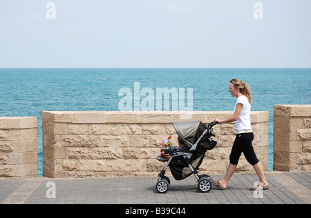 Israel-Tel Aviv-Jaffa Frau schob einen Kinderwagen an der Strand-promenade Stockfoto