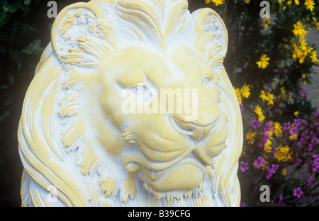 Detail des Kopf und Mähne aus Zement Löwenstatue gemalt, Creme und weiß im Garten mit Kränen Bill und Heliopsis hinter Stockfoto