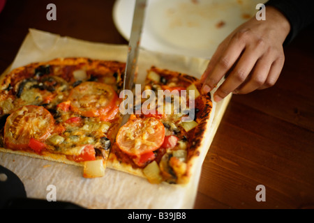 Hausgemachte Pizza indische Frau schneidet ein Stück Stockfoto