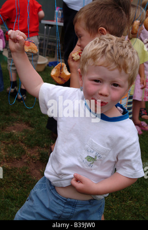 Kleiner Junge Essen Donuts aus einer Zeichenfolge Stockfoto