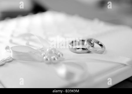 Zwei Trauringe, warten auf Besitzer, übereinander auf einem Stoff bedeckt Hochzeit Buch gezeigt Stockfoto