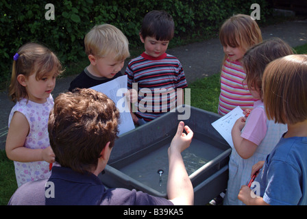Kinder draußen herumstehen ein Wasser-Tisch Stockfoto