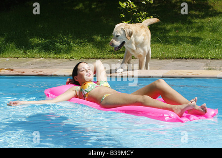 Labrador Retriever betrachten Frau auf Luftmatratze schlafen Stockfoto