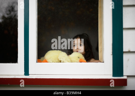 Mädchen im Alter von 5 blickt Fenster halten Stofftier Ente Stockfoto