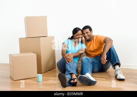 Afrikanische amerikanische männliche und weibliche Paar sitzt am Boden neben Umzugskartons Stockfoto