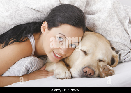 junge Frau und Labrador Retriever im Bett Stockfoto