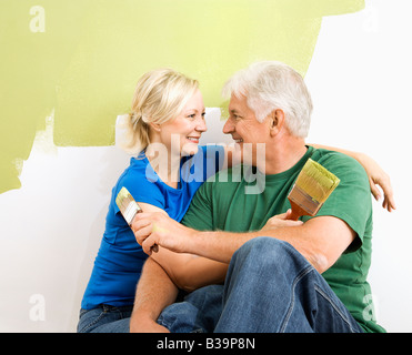 Applying paar kuscheln vor Wand, sie sind grün malen Stockfoto