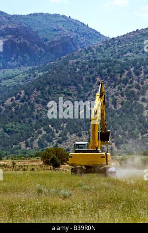 Foto von einem großen Bagger verfolgt Bagger arbeiten und dazu beitragen, um ein neues Haus zu bauen. In einem Feld-Hof. Baumaschinen. Stockfoto