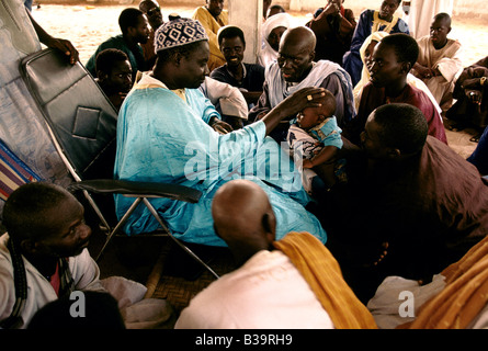 "TOUBA, AFRIKAS WENIG MEKKA" GLÄUBIGEN HULDIGEN UND HABEN IHR BABY GESEGNET DURCH IHRE MARABOUT, 1996 Stockfoto