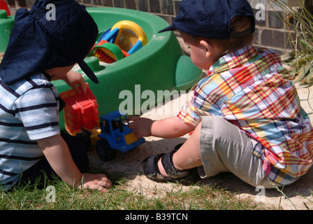 Zwei kleine Jungs spielen mit Baggern im sand Stockfoto