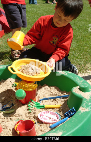 Kleiner Junge spielt mit Spielzeug in einem Sandkasten Stockfoto