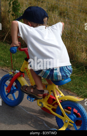 Rückansicht eines kleinen Jungen auf Fahrrad mit Stabilisatoren Stockfoto