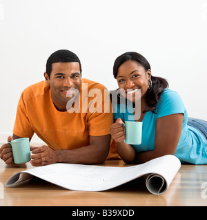 Afrikanische amerikanische männliche und weibliche Paar mit Architekturpläne Kaffeetrinken Stockfoto