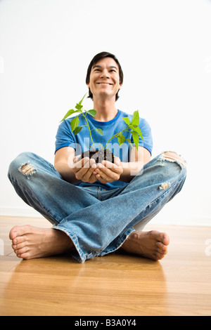 Asiatischer Mann sitzen halten Cayenne Pflanze wächst Stockfoto