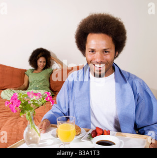 Afrikanischer Mann mit Frühstück im Bett Tablett Stockfoto