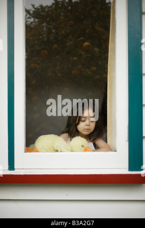 Mädchen im Alter von 5 blickt Fenster halten Stofftier Ente Stockfoto