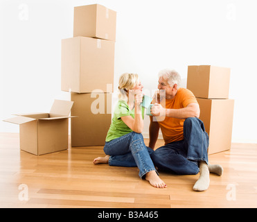 Mittleren gealterten paar am Boden unter Karton bewegen Boxen Kaffee trinken Stockfoto