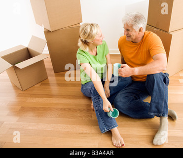 Mittleren gealterten paar am Boden unter Karton bewegen Boxen Kaffee trinken Stockfoto