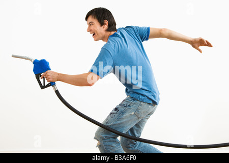 Asiatische junge Mann mit dem Ziel Benzin Pumpe Düse wie eine Waffe Stockfoto