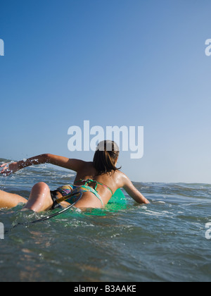 Hispanischen Mädchen auf Surfbrett paddeln Stockfoto