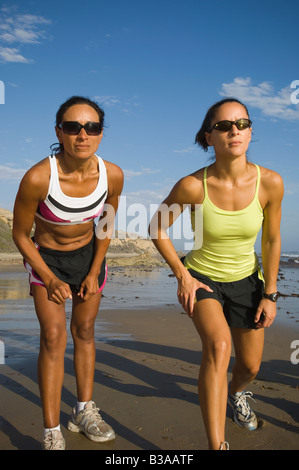 Hispanische Läuferinnen Rennen am Strand Stockfoto