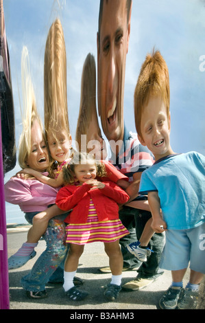 Eine Familie spiegelt sich in einen alten Messegelände Spiegel am Strand von Brighton während einem Tag am Meer. Stockfoto