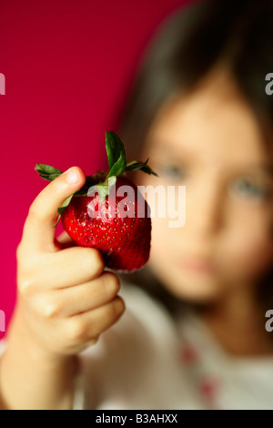 Fünf Jahre altes Mädchen hält Erdbeere Stockfoto