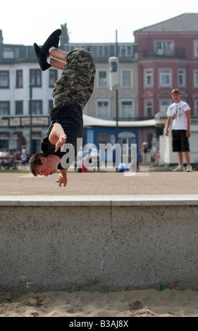 Ein "free Runner" Saltos vor dem Deich bei Great Yarmouth, England Stockfoto