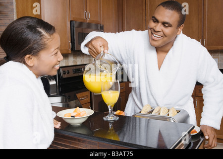 Afrikanischer Mann Gießen Orangensaft für Frau Stockfoto