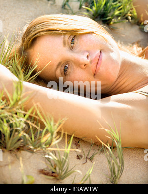 Nahaufnahme Portrait attraktive rothaarige Frau liegend in grasbewachsenen Sand Viewer betrachten Stockfoto