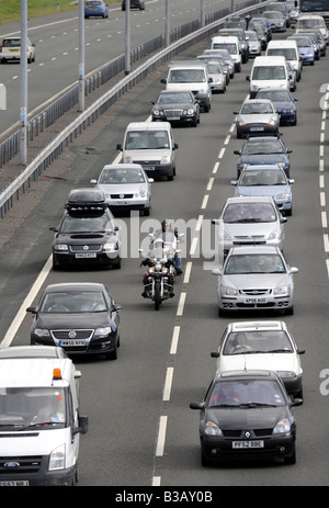 MOTORRADFAHRER, DIE FILTERUNG DURCH STOCKENDER VERKEHR AUF DER AUTOBAHN M6 AUTOBAHN BEI AUSFAHRT 11, STAFFORDSHIRE, UK. Stockfoto