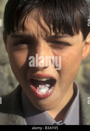 Junge mit Sorbet Pulver zischt in seinem Mund Zitronensäure + Natron gibt Natriumcitrat + Wasser + Kohlendioxid Stockfoto